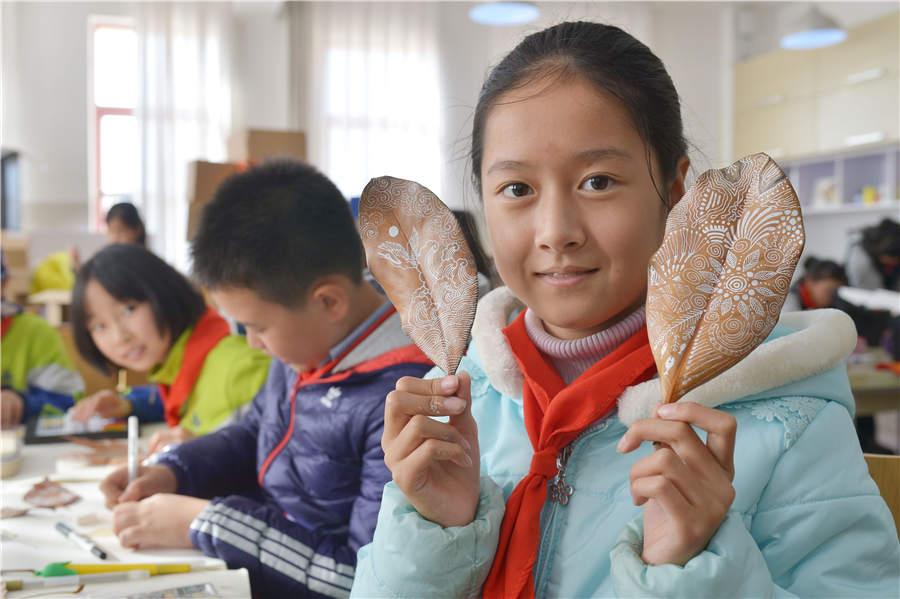 A student shows her leaf art at a primary school in Qingdao, East China\'s Shandong Province, on Nov. 19, 2018. (Photo/Asianewsphoto)