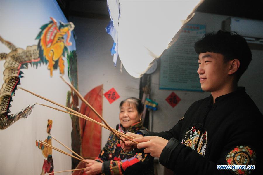 Liu Fan(R), one of Zhang Kunrong\'s apprentices, performs in a shadow puppetry show in Haining City, east China\'s Zhejiang Province, Nov. 21, 2018. Zhang Kunrong, 79, a locally born shadow puppetry player, is an inheritor of the Haining shadow puppetry, a form of traditional theatre acted by colorful silhouette figures made from leather or paper, accompanied by music and singing. A typical variety popular in south China, Haining shadow puppetry, a national intangible cultural heritage, has a history of about 900 years dating back to the Southern Song Dynasty (AD 1127-1279). Obsessed with the shadow play since childhood, Zhang Kunrong was recruited to the provincial shadow puppetry troupe in 1958 and soon became a mainstay after two year\'s practice and in the later years staged performances at home and abroad as Haining shadow puppetry grows popular. Nowadays, Zhang works more on script writing, directing and teaching apprentices. Haining shadow puppetry was listed as one of the state-level intangible cultural heritages in 2006 and was included in the UNESCO Intangible Cultural Heritage of Humanity list in 2011. (Xinhua/Zhu Weixi)