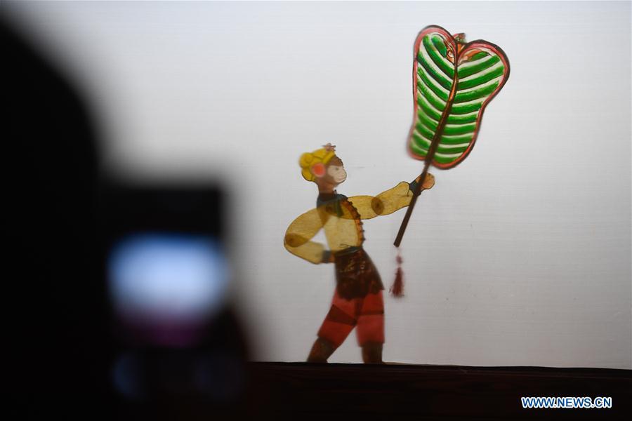 A spectator takes a photo during a shadow puppetry show in Haining City, east China\'s Zhejiang Province, Nov. 21, 2018. Zhang Kunrong, 79, a locally born shadow puppetry player, is an inheritor of the Haining shadow puppetry, a form of traditional theatre acted by colorful silhouette figures made from leather or paper, accompanied by music and singing. A typical variety popular in south China, Haining shadow puppetry, a national intangible cultural heritage, has a history of about 900 years dating back to the Southern Song Dynasty (AD 1127-1279). Obsessed with the shadow play since childhood, Zhang Kunrong was recruited to the provincial shadow puppetry troupe in 1958 and soon became a mainstay after two year\'s practice and in the later years staged performances at home and abroad as Haining shadow puppetry grows popular. Nowadays, Zhang works more on script writing, directing and teaching apprentices. Haining shadow puppetry was listed as one of the state-level intangible cultural heritages in 2006 and was included in the UNESCO Intangible Cultural Heritage of Humanity list in 2011. (Xinhua/Huang Zongzhi)
