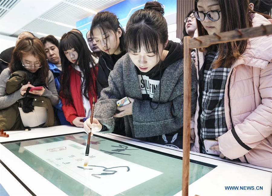 Visitors experience intelligent calligraphy writing desk during a major exhibition to commemorate the 40th anniversary of China\'s reform and opening-up at the National Museum of China in Beijing, capital of China, Nov. 24, 2018. (Xinhua/Yin Gang)