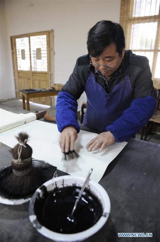Lei Shitai works on a paper as he prints a book in Chanshan Village of Qinxi Town, Jingxian County, in east China\'s Anhui Province, Nov. 23, 2018. Lei, 52, born in neighboring Jiangxi Province, started his career as a typography printer when he finished his apprenticeship with his uncle who he followed since he was 17. The traditional printing method witnessed an increasingly hard time in the recent years as a livelihood. It was in 2017 when he decided to move to Chanshan at the invitation of Kai Yuanhong, a local cabinet maker, to cooperate in a broader way. Lei is now working with the traditional technique in a larger scale. (Xinhua/Xu Liang)