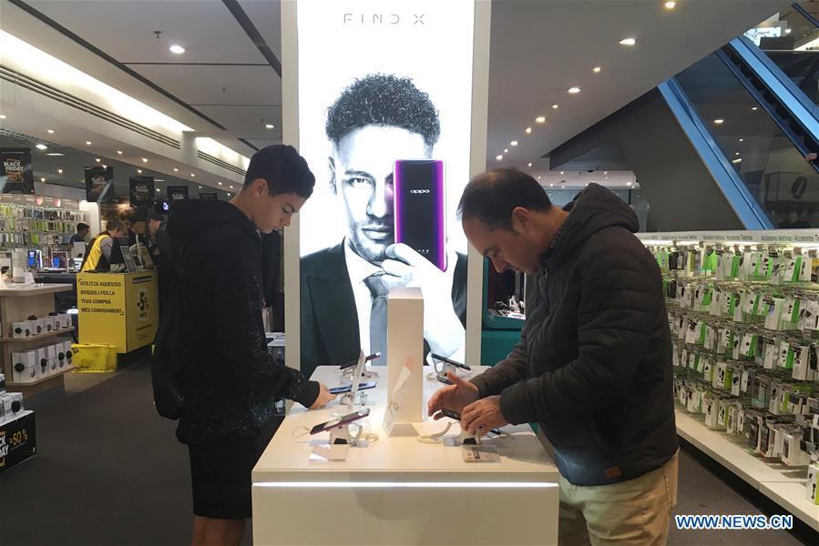 People select OPPO smart phones in a shopping mall in Barcelona, Spain, on Nov. 25, 2018. More and more Spanish consumers accept Chinese high-tech brands, which now can be seen in daily life across Spain. (Xinhua/Zheng Huansong)