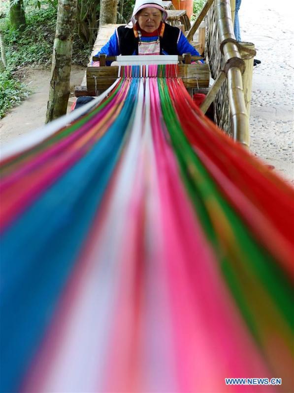 A Jino woman weaves cloths using a traditional hand loom in Bapo Village of Jinuo Ethnic Township on Jino Mountain in Jinghong of Xishuangbanna Dai Autonomous Prefecture, southwest China\'s Yunnan Province, Nov. 5, 2015. With a population of slightly over 20,000, the Jino people had only been officially acknowledged in 1979 as an independent ethnic group of China. Until 1949, most of them had lived for generations in primitive mountain tribes in southwest China\'s Yunnan Province. Over the four decades since it embraced the reform and opening-up policy, China has spared no effort to support ethnic groups with smaller populations. Life on Jino Mountain, where most Jino communities are located, saw positive changes in parallel with improvements in local politics, economy, technology, education, culture, health care, ecology, ethnic development and other social undertakings. Just like its 55 ethnic brethren, the Jino people also benefit from China\'s reform and opening-up in seeking a prosperous life. In Jino Ethnic Township on the Jino Mountain, residents now have direct access to road, water, electricity, TV and radio, as well as the mobile network. Ninety percent of the residents have moved into new houses. Most residents own motorcycles and tractors, and some of them have purchased cars. More people have increased their income by selling local specialty products via the internet, whereas in the past, doing business was perceived as a shame. Currently, the primary education in Jino Ethnic Township achieved 100 percent coverage for all school-age children. More than 99 percent of residents have joined the rural cooperative medical insurance programme. The Jino ethnic culture undergoes protection and inheritance: the great drum dance of the Jino people has been listed as one of China\'s national intangible cultural heritages. (Xinhua/Lin Yiguang)