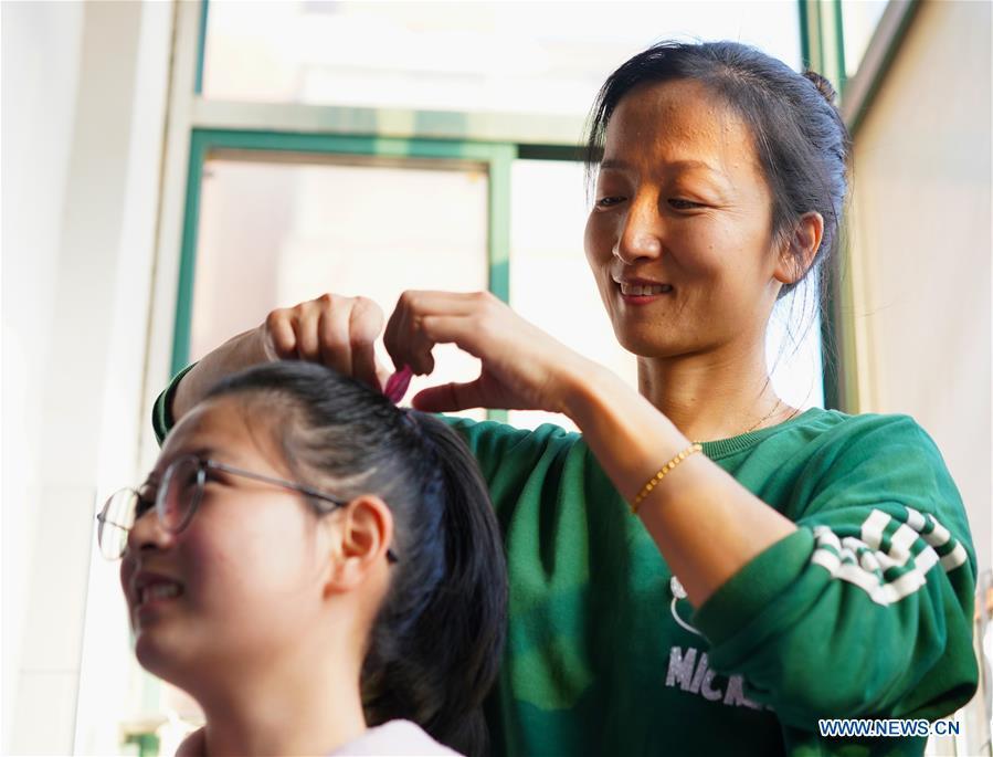 Teacher Zeng Wenping (R) combs a student\'s hair at Qiyin school in Nanchang, capital of east China\'s Jiangxi Province, Nov. 26, 2018. Zeng, 43, has been engaged in special education for 21 years ever since she graduated from university. Hearing impaired students enjoy the all-encompassing heartfelt and intensive care by Zeng and consider her as more than a teacher but a sister. (Xinhua/Hu Chenhuan)