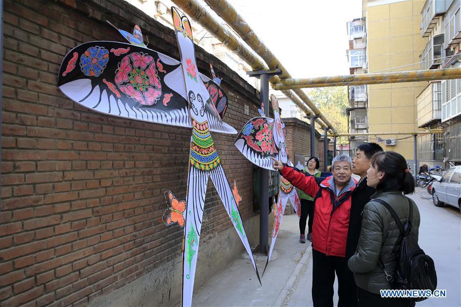 Fu Xianming (1st L, front) introduces self-made kites to neighbors in Shijiazhuang, capital of north China\'s Hebei Province, Nov. 21, 2018. Fu Xianming, a 66-year-old craftsman, has devoted himself in kites making for 20 years. Fu and his wife have made more than 1,500 kites of various shapes since 1998. (Xinhua/Zhang Haiqiang)