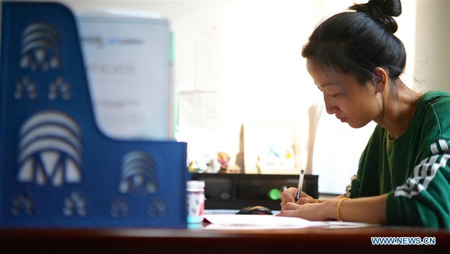 Teacher Zeng Wenping prepares lectures at Qiyin school in Nanchang, capital of east China\'s Jiangxi Province, Nov. 26, 2018. Zeng, 43, has been engaged in special education for 21 years ever since she graduated from university. Hearing impaired students enjoy the all-encompassing heartfelt and intensive care by Zeng and consider her as more than a teacher but a sister. (Xinhua/Hu Chenhuan)