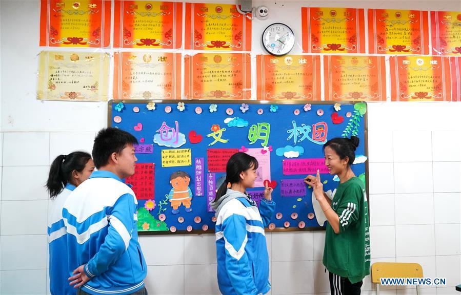 Teacher Zeng Wenping (R) communicates with students as they work together on the blackboard newspaper at Qiyin school in Nanchang, capital of east China\'s Jiangxi Province, Nov. 26, 2018. Zeng, 43, has been engaged in special education for 21 years ever since she graduated from university. Hearing impaired students enjoy the all-encompassing heartfelt and intensive care by Zeng and consider her as more than a teacher but a sister. (Xinhua/Hu Chenhuan)