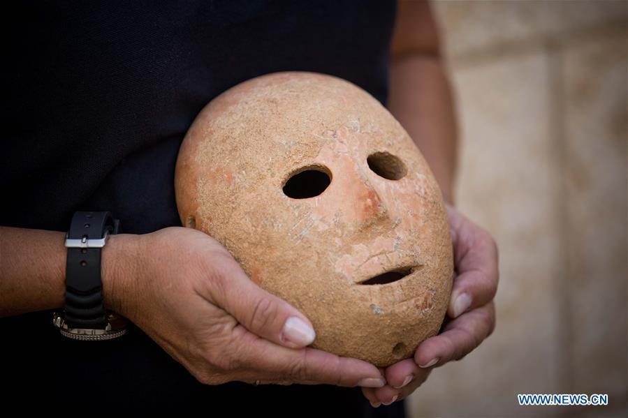 Ronit Lupu, an archeologist from the Israel Antiquities Authority (IAA), holds a stone mask at the Rockefeller Museum in Jerusalem, on Nov. 28, 2018. A rare pre-historic stone mask, dating back to the Pre-Pottery Neolithic B (PPNB) period 9,000 years ago, was discovered in the southern West Bank, the Israel Antiquities Authority said Wednesday. (Xinhua/JINI)