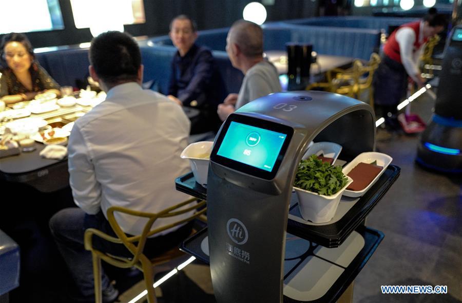 A delivery robot sends dishes to tables at a hot pot restaurant in Beijing, capital of China, Dec. 5, 2018. A hot pot restaurant which integrates artificial intelligence, big data management and smart robot service has attracted lots of consumers. After customers order their dishes with a tablet computer, robotic arms in the kitchen get all dishes ready and then the delivery robots sent the dishes to the tables. Workers in the kitchen control all the procedures and also monitor the data for better management. (Xinhua/Zhang Chen)