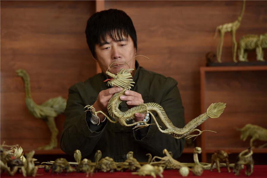 Craftsman Han Liuye works with one of his straw-plaited artworks on December 3 in Zhangjiakou, Hebei Province. (Photo provided to chinadaily.com.cn)