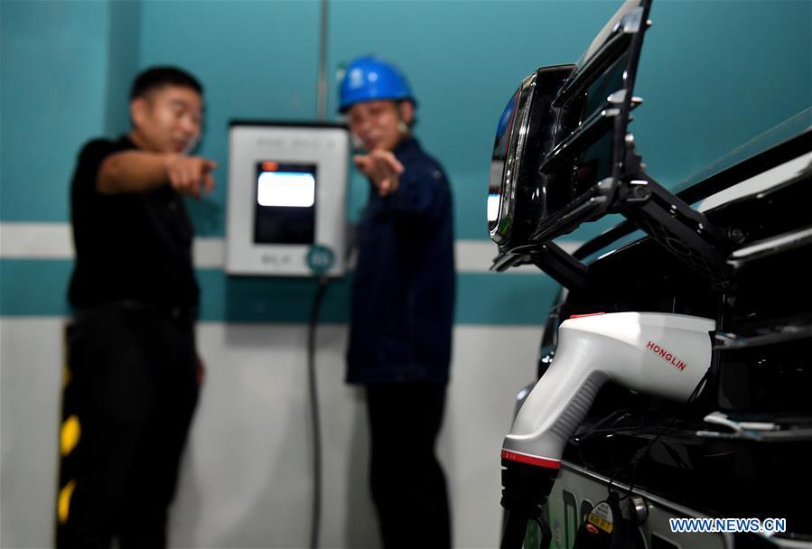 A staff introduces to a citizen the charging notice for new energy cars in Zhengzhou, capital of central China\'s Henan Province, July 18, 2018. China has been delivering on its commitment to the international community on climate change by continuously shifting to a more green economy over the past years. New energy-rich regions like Inner Mongolia and Ningxia are sending more electricity generated from clean energy to the country\'s bustling east to help reduce the country\'s heavy reliance on coal in the fight against pollution and coping with climate change. China is also a leader in new energy vehicles (NEVs), with many regions across the country moving to replace their traditional gasoline-powered buses and taxis with green-energy vehicles. The country has been the world\'s largest NEV market for three consecutive years, with some 777,000 NEVs sold in 2017 alone. Sales in the first 10 months of this year jumped 75.6 percent year on year to 860,000 units. Thanks to increased investment in green energy, China\'s carbon intensity, or the amount of carbon dioxide emissions per unit of GDP, in 2017 had declined by 46 percent from 2005 levels, meeting the target ahead of schedule of a 40-45 percent drop by 2020, according to the Chinese Ministry of Ecology and Environment. (Xinhua/Li Jianan)