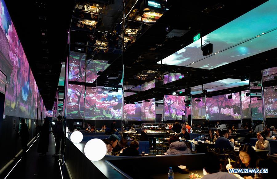 Customers enjoy their meals at a hot pot restaurant in Beijing, capital of China, Dec. 5, 2018. A hot pot restaurant which integrates artificial intelligence, big data management and smart robot service has attracted lots of consumers. After customers order their dishes with a tablet computer, robotic arms in the kitchen get all dishes ready and then the delivery robots sent the dishes to the tables. Workers in the kitchen control all the procedures and also monitor the data for better management. (Xinhua/Zhang Chen)