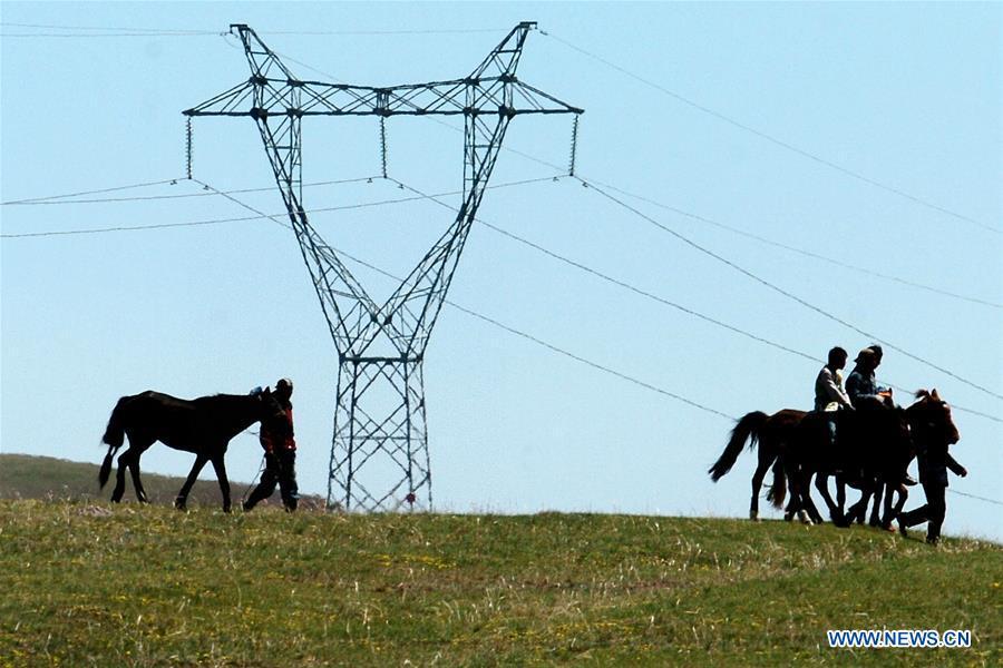 Herdsmen ride horses near a wind power plant in Hexigten Qi of north China\'s Inner Mongolia Autonomous Region, May 19, 2007. China has been delivering on its commitment to the international community on climate change by continuously shifting to a more green economy over the past years. New energy-rich regions like Inner Mongolia and Ningxia are sending more electricity generated from clean energy to the country\'s bustling east to help reduce the country\'s heavy reliance on coal in the fight against pollution and coping with climate change. China is also a leader in new energy vehicles (NEVs), with many regions across the country moving to replace their traditional gasoline-powered buses and taxis with green-energy vehicles. The country has been the world\'s largest NEV market for three consecutive years, with some 777,000 NEVs sold in 2017 alone. Sales in the first 10 months of this year jumped 75.6 percent year on year to 860,000 units. Thanks to increased investment in green energy, China\'s carbon intensity, or the amount of carbon dioxide emissions per unit of GDP, in 2017 had declined by 46 percent from 2005 levels, meeting the target ahead of schedule of a 40-45 percent drop by 2020, according to the Chinese Ministry of Ecology and Environment. (Xinhua/Zhang Ling)