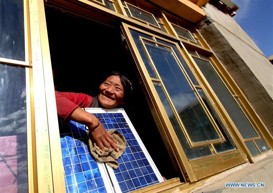 A woman cleans a solar panel at her new house thanks to the \