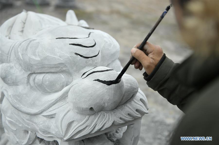 A handicraftsman sketches on a rock carving work for further processing in Longdong Village of Xuan\'en County in Enshi Tujia and Miao Autonomous Prefecture, central China\'s Hubei Province, Dec. 5, 2018. Residents here benefit from the rich rock resources and turn plain rocks into delicate artworks. (Xinhua/Song Wen)