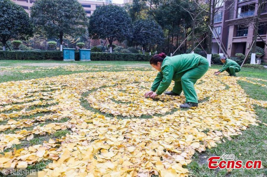 Sanitation workers collect fallen leaves and use them to form various patterns on ground in Qingyang district of Chengdu, Southwest China’s Sichuan province on December 4, 2018. (Photo/VCG)