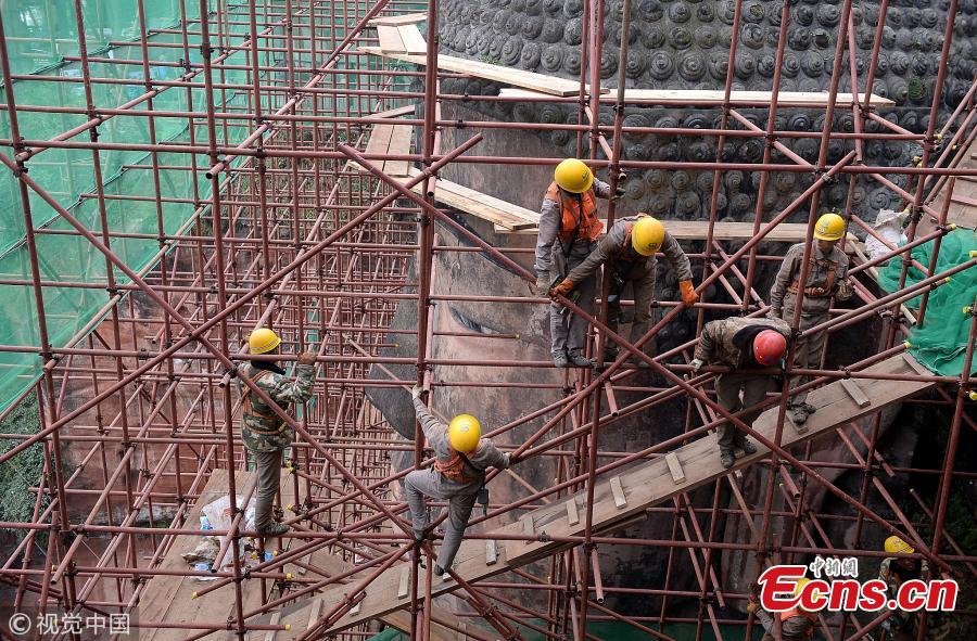 A 71-meter-tall Buddha statue-enclosed by scaffolding in the Leshan Giant Buddha Scenic Zone in Leshan, Sichuan province-has been undergoing repairs and maintenance since Oct 8. The price of entrance tickets to the scenic zone were cut by half on Monday because of the work, according to its administrative committee.(Photo/VCG)