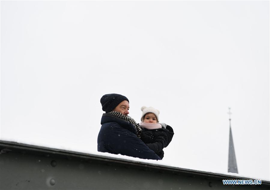 A man with a child stands on the Eiserner Steg footbridge amid snow in Frankfurt, Germany, on Dec. 16, 2018. A snowfall hit Frankfurt on Sunday. (Xinhua/Lu Yang)