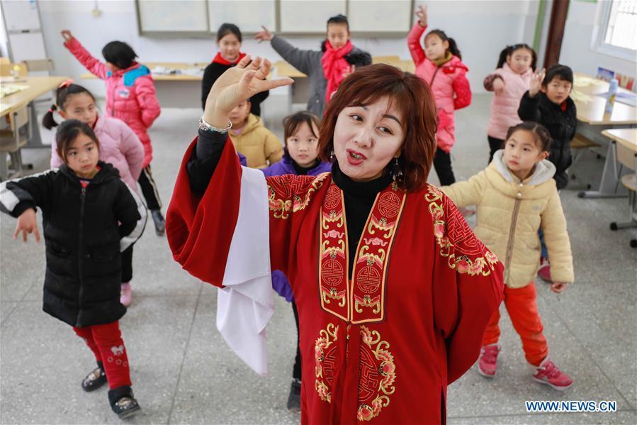 Bi Chunmei, a performer of Xuyi Huangmei Opera Troupe, teaches students Huangmei Opera at Gusang Primary School, in Xuyi County of east China\'s Jiangsu Province, Dec. 16, 2018. Performers of the troupe have been teaching local students Huangmei Opera in recent years to promote the traditional opera. (Xinhua/Zhou Haijun)