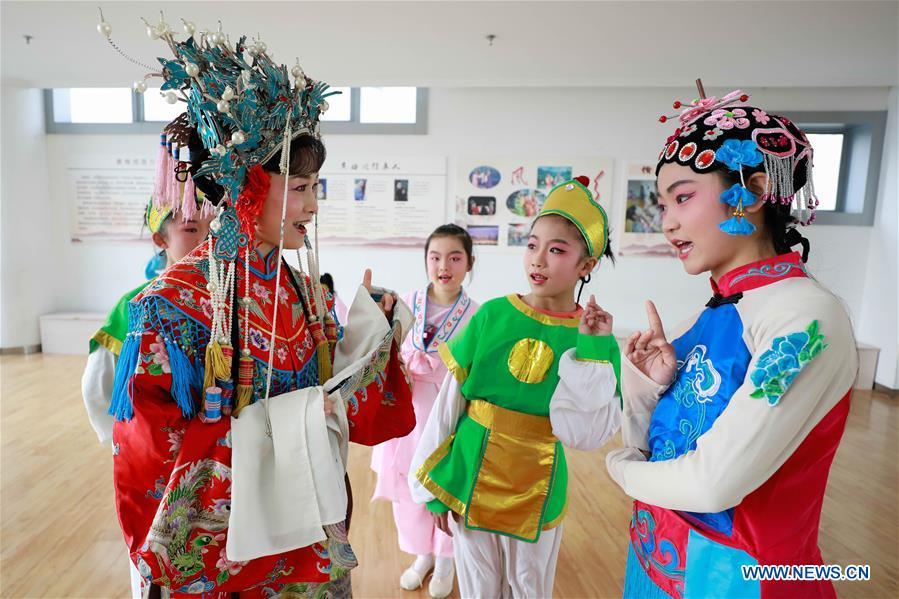 Meng Qingmei (L, front), a performer of Xuyi Huangmei Opera Troupe, teaches students Huangmei Opera, in Xuyi County of east China\'s Jiangsu Province, Dec. 16, 2018. Performers of the troupe have been teaching local students Huangmei Opera in recent years to promote the traditional opera. (Xinhua/Zhou Haijun)