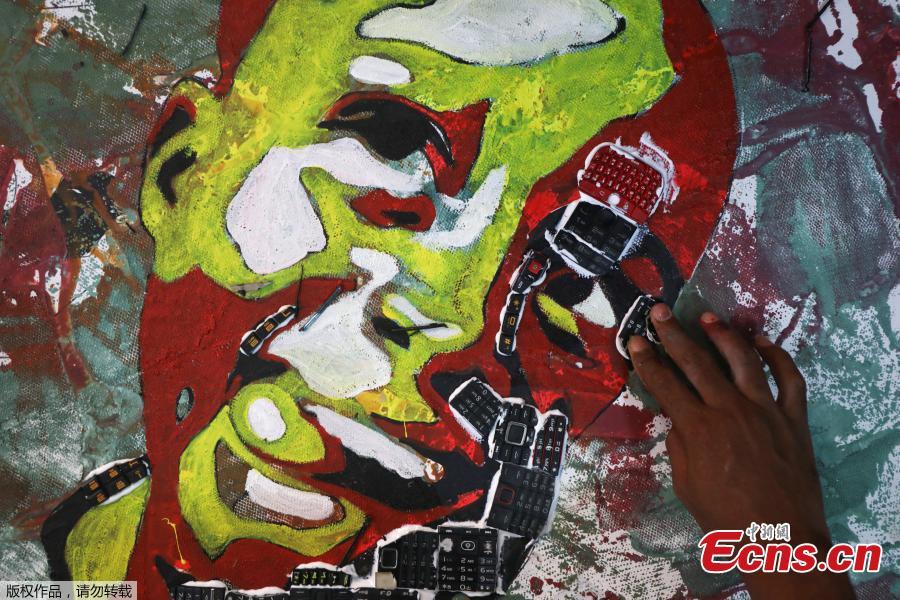Desire Koffi, 24-year-old artist, places electronic waste on his painting at his workshop in Abidjan, Ivory Coast, Dec. 5, 2018. Desire Koffi often walks through Koumassi, a popular district of Ivory Coast\'s main city Abidjan, to collect old mobile phones that he buys from people for 500 CFA francs ($0.8726) a pair. Back home, he dismantles the phones with a hammer to pull out the screens and keyboards. He uses them for his paintings. One can take him up to three or five days of work. (Photo/Agencies)