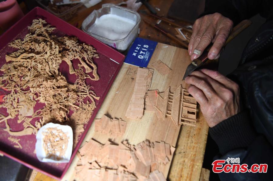 A craftsman carves on bark at a workshop in Fuzhou City, East China\'s Fujian Province. As an intangible cultural heritage, bark carving is regarded as one of the three treasures of Fujian. Craftsmen can carve elaborate scenes, including pavilions, bridges and landscape features, onto the bark. The craft is in decline today as fewer young people are interested in the time-consuming profession. (Photo: China News Service/Zhang Bin)