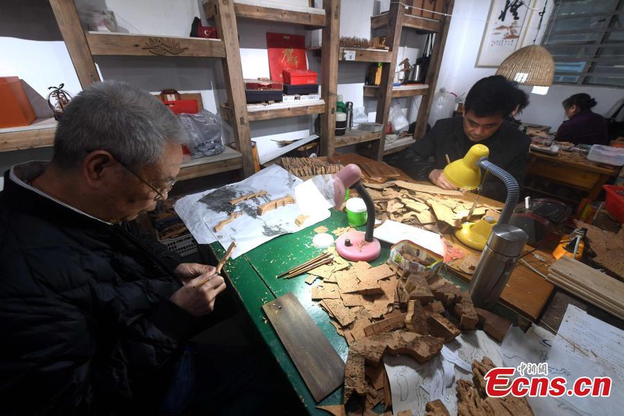 Craftsmen carve on bark at a workshop in Fuzhou City, East China\'s Fujian Province. As an intangible cultural heritage, bark carving is regarded as one of the three treasures of Fujian. Craftsmen can carve elaborate scenes, including pavilions, bridges and landscape features, onto the bark. The craft is in decline today as fewer young people are interested in the time-consuming profession. (Photo: China News Service/Zhang Bin)