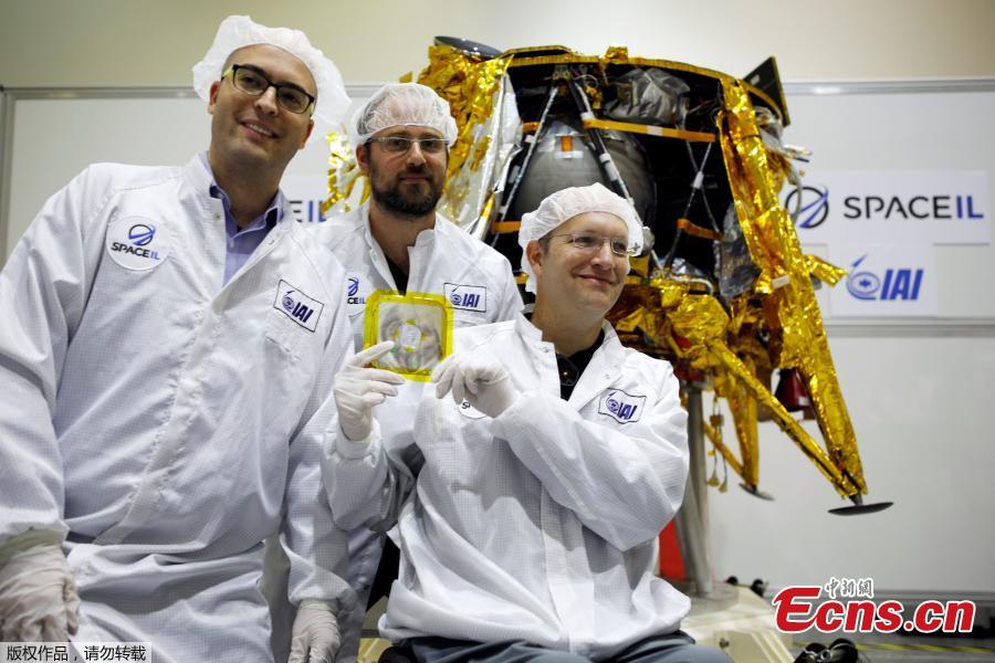 Members of Israeli non-profit group SpaceIL and representatives from Israel Aerospace Industries (IAI) hold a time capsule next to an unmanned spacecraft during a presentation to the media of the time capsule, intended to travel to the moon with the spacecraft in early 2019, at the clean room of IAI\'s space division in Yehud, Israel Dec. 17, 2018. (Photo/Agencies)