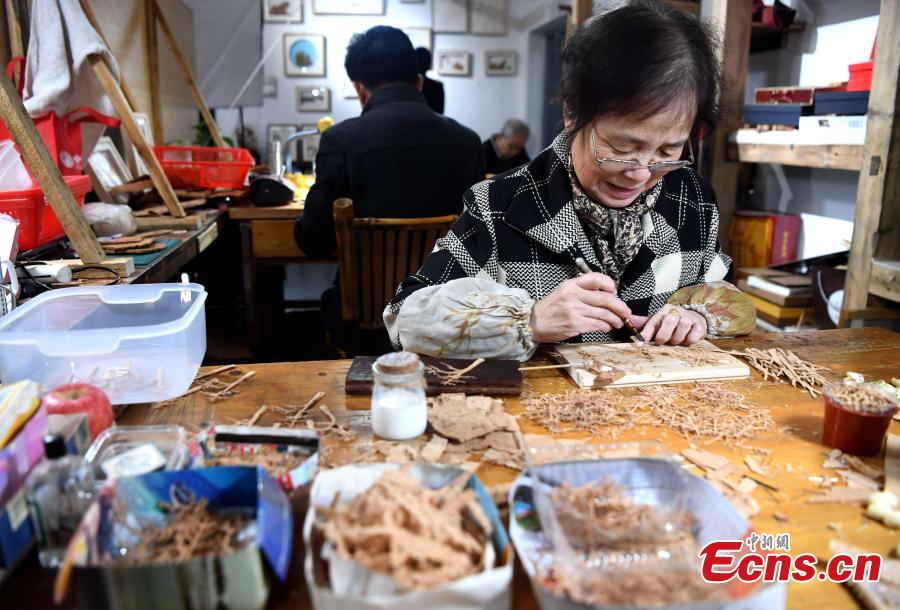 Folk artist Chen Xuerong, who has practiced the craft for 60 years, carves on bark at a workshop in Fuzhou City, East China\'s Fujian Province. As an intangible cultural heritage, bark carving is regarded as one of the three treasures of Fujian. Craftsmen can carve elaborate scenes, including pavilions, bridges and landscape features, onto the bark. The craft is in decline today as fewer young people are interested in the time-consuming profession. (Photo: China News Service/Zhang Bin)