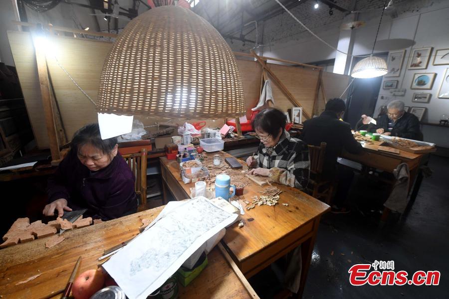 Folk artist Chen Xuerong, who has practiced the craft for 60 years, carves on bark at a workshop in Fuzhou City, East China\'s Fujian Province. As an intangible cultural heritage, bark carving is regarded as one of the three treasures of Fujian. Craftsmen can carve elaborate scenes, including pavilions, bridges and landscape features, onto the bark. The craft is in decline today as fewer young people are interested in the time-consuming profession. (Photo: China News Service/Zhang Bin)