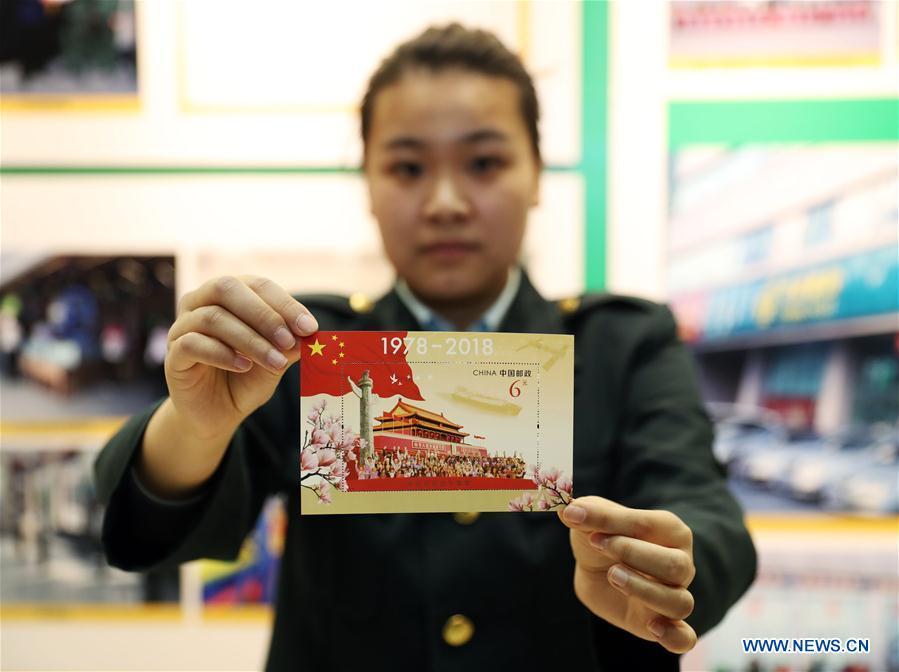 A staff member shows the souvenir sheet marking the 40th anniversary of China\'s reform and opening up at the post office of Liaoning provincial archives in Shenyang, capital of northeast China\'s Liaoning Province, Dec. 18, 2018. China Post released a set of commemorative stamps and one souvenir sheet marking the 40th anniversary of China\'s reform and opening up on Tuesday. (Xinhua/Yang Qing)