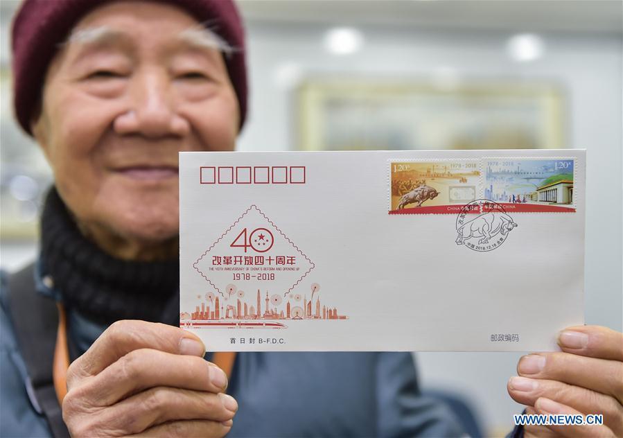 Chang Rongguang, an 82-year-old stamp collector, shows the first day cover with stamps released to mark the 40th anniversary of China\'s reform and opening up at a post office in Xicheng District of Beijing, capital of China, Dec. 18, 2018. China Post released a set of commemorative stamps and one souvenir sheet marking the 40th anniversary of China\'s reform and opening up on Tuesday. (Xinhua/Li He)