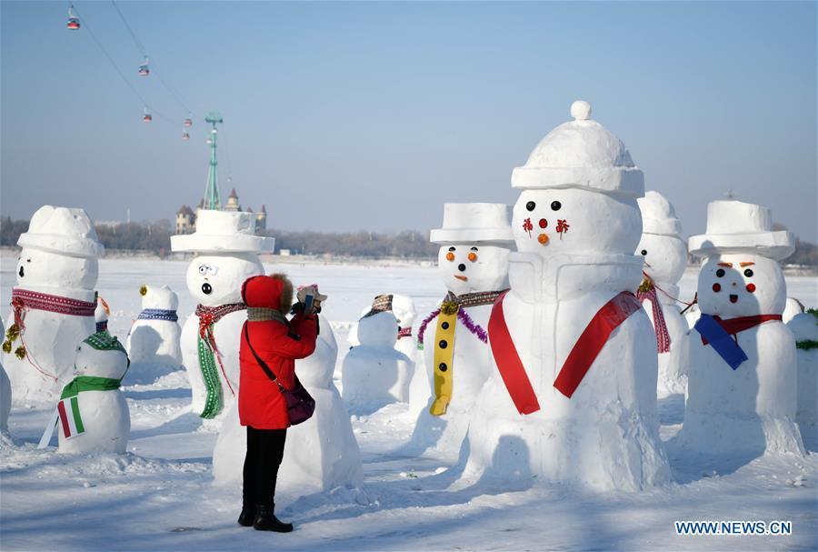 A woman takes photos of snowman sculptures on the riverbank of Songhua River in Harbin, capital of northeast China\'s Heilongjiang Province, Jan. 2, 2019. Altogether 2,019 cute snowmen were displayed here to greet the year 2019. (Xinhua/Wang Jianwei)
