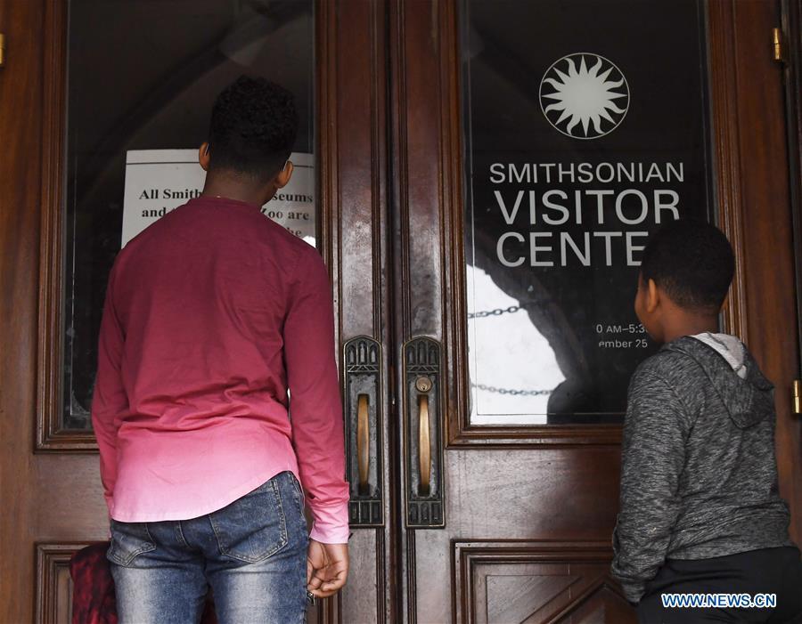 People stand in front of the closed doors of the Smithsonian Institution Building\'s visitor center in Washington D.C., the United States, on Jan. 2, 2019. The 19 Smithsonian museums and the National Zoo in Washington D.C. closed their doors on Wednesday as the partial U.S. government shutdown dragged on. (Xinhua/Liu Jie)