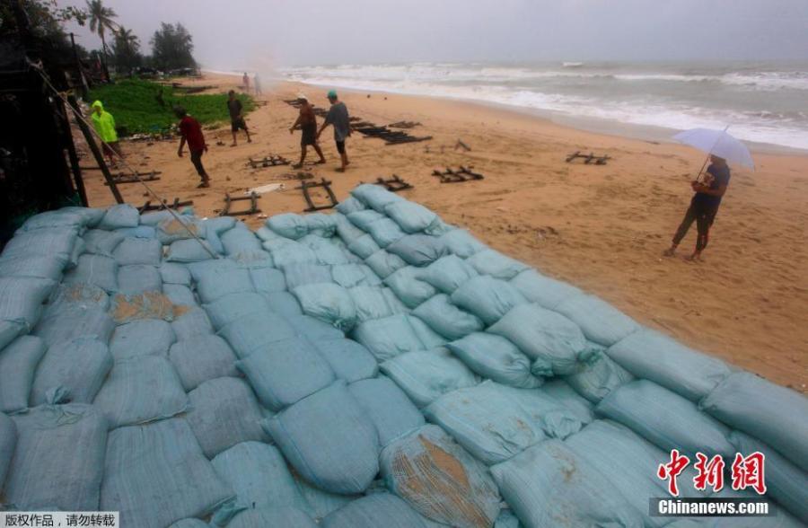 People walk close to a sandbank, which was built to protect properties of seaside communities in Songkhla, Thailand on Thursday, Jan. 3, 2019. Thai weather authorities are warning that a tropical storm will bring heavy rains and high seas to southern Thailand and its famed beach resorts. (Photo/Agencies)