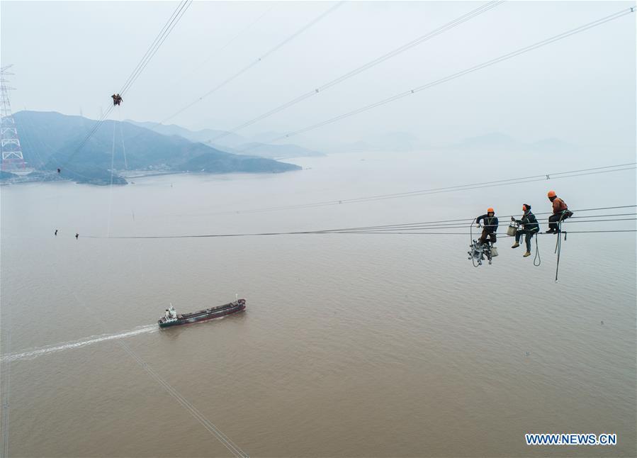 Staff members work on the cables at the site of the giant power supply pylons in Zhoushan, east China\'s Zhejiang Province, Jan. 3, 2019. The two 380-meter-tall pylons carry power cables between Zhoushan\'s Jintang and Cezi islands, a distance of 2,656 meters. The new pylon project is a part of a new ultra-high voltage power line project between cities of Zhoushan and Ningbo. (Xinhua/Xu Yu)