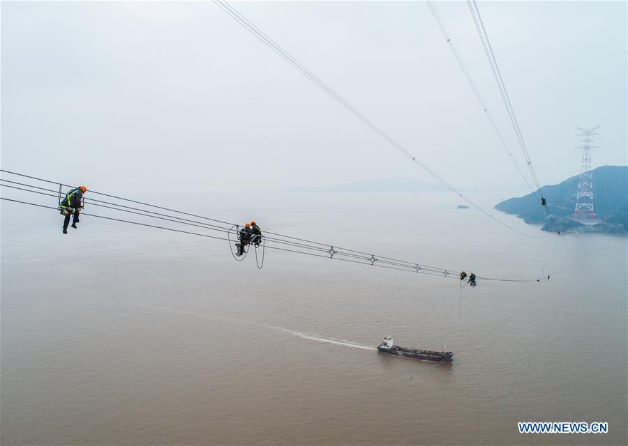 Staff members work on the cables at the site of the giant power supply pylons in Zhoushan, east China\'s Zhejiang Province, Jan. 3, 2019. The two 380-meter-tall pylons carry power cables between Zhoushan\'s Jintang and Cezi islands, a distance of 2,656 meters. The new pylon project is a part of a new ultra-high voltage power line project between cities of Zhoushan and Ningbo. (Xinhua/Xu Yu)