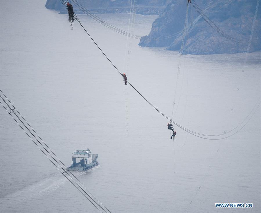 Staff members work on the cables at the site of the giant power supply pylons in Zhoushan, east China\'s Zhejiang Province, Jan. 3, 2019. The two 380-meter-tall pylons carry power cables between Zhoushan\'s Jintang and Cezi islands, a distance of 2,656 meters. The new pylon project is a part of a new ultra-high voltage power line project between cities of Zhoushan and Ningbo. (Xinhua/Xu Yu)