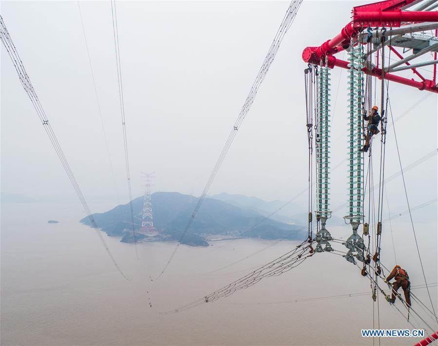 Staff members work on the cables at the site of the giant power supply pylons in Zhoushan, east China\'s Zhejiang Province, Jan. 3, 2019. The two 380-meter-tall pylons carry power cables between Zhoushan\'s Jintang and Cezi islands, a distance of 2,656 meters. The new pylon project is a part of a new ultra-high voltage power line project between cities of Zhoushan and Ningbo. (Xinhua/Xu Yu)
