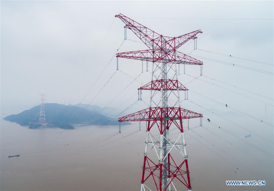 Staff members work on the cables at the site of the giant power supply pylons in Zhoushan, east China\'s Zhejiang Province, Jan. 3, 2019. The two 380-meter-tall pylons carry power cables between Zhoushan\'s Jintang and Cezi islands, a distance of 2,656 meters. The new pylon project is a part of a new ultra-high voltage power line project between cities of Zhoushan and Ningbo. (Xinhua/Xu Yu)