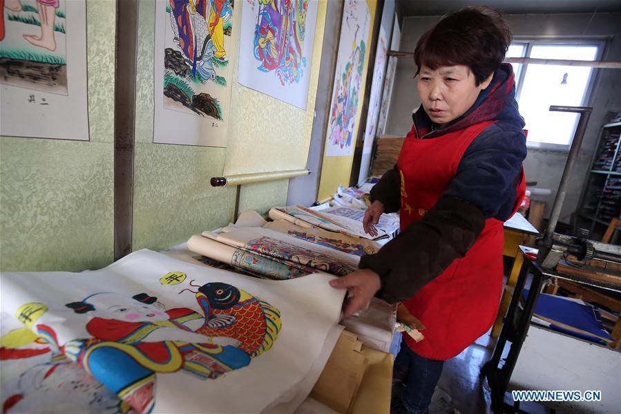 A folk artist arranges woodblock New Year paintings in Yangjiabu Village of Hanting District in Weifang, east China\'s Shandong Province, Jan. 8, 2019. Local folk artists are busy making woodblock New Year paintings for the upcoming Spring Festival, which starts from the first day of the first month of the Chinese lunar calendar, or Feb. 5 this year. (Xinhua/Zhang Chi)