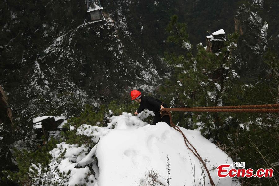 Su Songyun braves the winter cold to abseil down a cliff face and collect rubbish at the Huangshizhai scenic area in Zhangjiajie City, Central China\'s Hunan Province, Jan. 15, 2019. The 34-year-old local farmer began learning the stunt from his father in 2005, and his daredevil antics entertain tourists and enable him to collect garbage otherwise inaccessible on the mountain slope. (Photo: China News Service/Wu Yongbing)