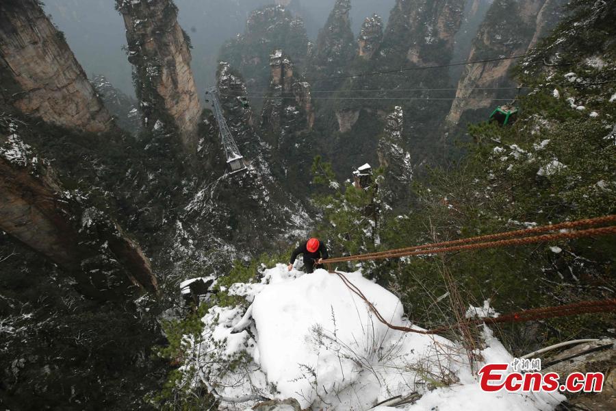 Su Songyun braves the winter cold to abseil down a cliff face and collect rubbish at the Huangshizhai scenic area in Zhangjiajie City, Central China\'s Hunan Province, Jan. 15, 2019. The 34-year-old local farmer began learning the stunt from his father in 2005, and his daredevil antics entertain tourists and enable him to collect garbage otherwise inaccessible on the mountain slope. (Photo: China News Service/Wu Yongbing)