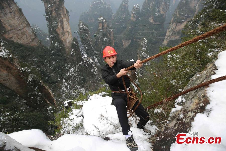 Su Songyun braves the winter cold to abseil down a cliff face and collect rubbish at the Huangshizhai scenic area in Zhangjiajie City, Central China\'s Hunan Province, Jan. 15, 2019. The 34-year-old local farmer began learning the stunt from his father in 2005, and his daredevil antics entertain tourists and enable him to collect garbage otherwise inaccessible on the mountain slope. (Photo: China News Service/Wu Yongbing)