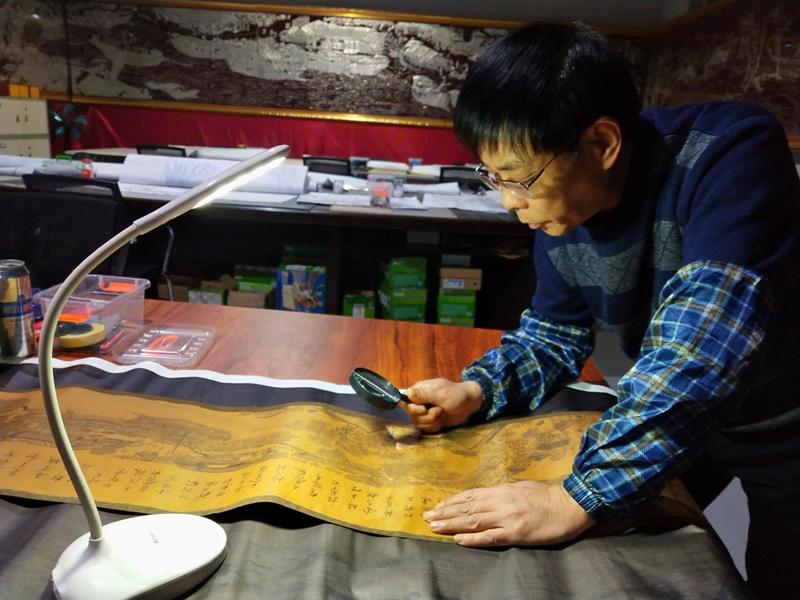 Gao Baoan studies a replica of the painting Riverside Scene at Qingming Festival.  (Photo provided to chinadaily.com.cn)