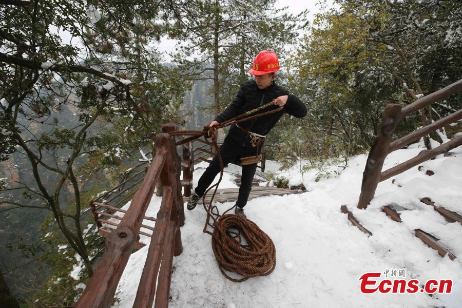 Su Songyun braves the winter cold to abseil down a cliff face and collect rubbish at the Huangshizhai scenic area in Zhangjiajie City, Central China\'s Hunan Province, Jan. 15, 2019. The 34-year-old local farmer began learning the stunt from his father in 2005, and his daredevil antics entertain tourists and enable him to collect garbage otherwise inaccessible on the mountain slope. (Photo: China News Service/Wu Yongbing)