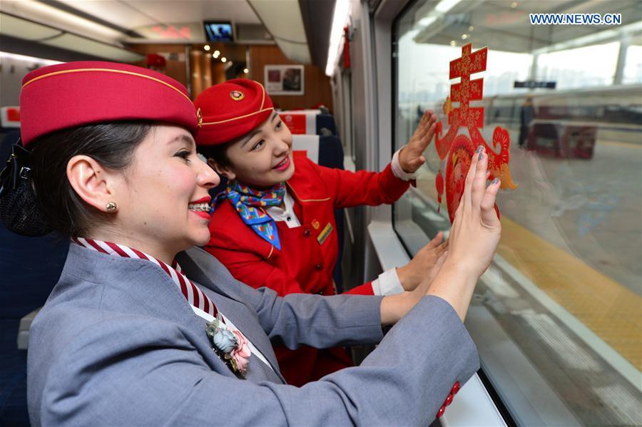 A foreign volunteer and the train staff member decorate the train cabin at Xi\'an North Railway Station in Xi\'an, capital of northwest China\'s Shaanxi Province, Jan. 20, 2019. Three foreign student volunteers from Xi\'an Jiaotong University came to Xi\'an North Railway Station on Sunday to familiarize themselves with the train staff members\' work. They would serve passengers during the Spring Festival travel rush. The Spring Festival, or the Year of the Pig in the Chinese lunar calendar, will begin on Feb. 5 this year. The 40-day 2019 Spring Festival travel rush started on Jan. 21, with 3 billion trips expected to be made. (Xinhua/Tang Zhenjiang)