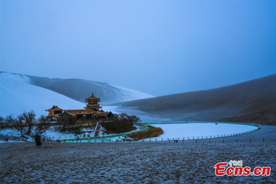 The Crescent Spring and Singing-Sand Dunes scenic spot in Dunhuang City, Northwest China\'s Gansu Province, after its first snow of the year, Jan. 19, 2019. Riding a camel across the desert landscape has become a popular activity for tourists to the area. (Photo: China News Service/Wang Binyin)