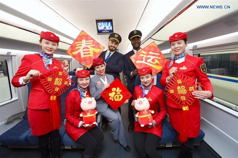 Train staff members pose for photos with foreign volunteers at Xi\'an North Railway Station in Xi\'an, capital of northwest China\'s Shaanxi Province, Jan. 20, 2019. Three foreign student volunteers from Xi\'an Jiaotong University came to Xi\'an North Railway Station on Sunday to familiarize themselves with the train staff members\' work. They would serve passengers during the Spring Festival travel rush. The Spring Festival, or the Year of the Pig in the Chinese lunar calendar, will begin on Feb. 5 this year. The 40-day 2019 Spring Festival travel rush started on Jan. 21, with 3 billion trips expected to be made. (Xinhua/Tang Zhenjiang)