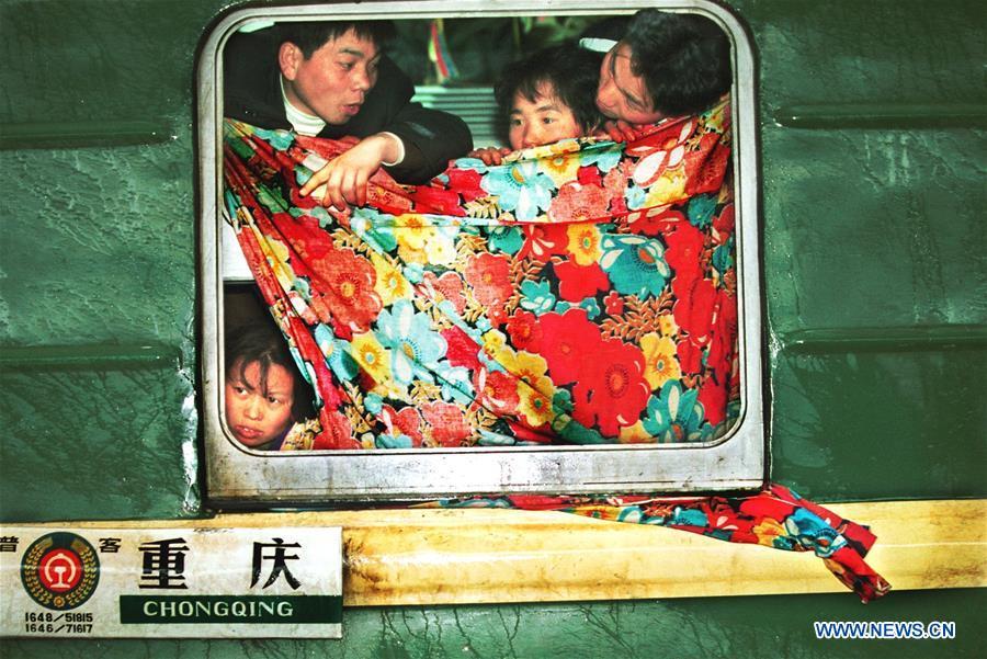 Passengers look outside through a windshielding bedsheet on a train at the Hankou Railway Station, central China\'s Hubei Province, Jan. 21, 2001. Returning to hometowns remains the most important part of the Chinese Spring Festival. Whether self-driving, or taking the trains or flights, homecomings and family gatherings are a priority for many Chinese. The annual travel rush around the festival, known as \